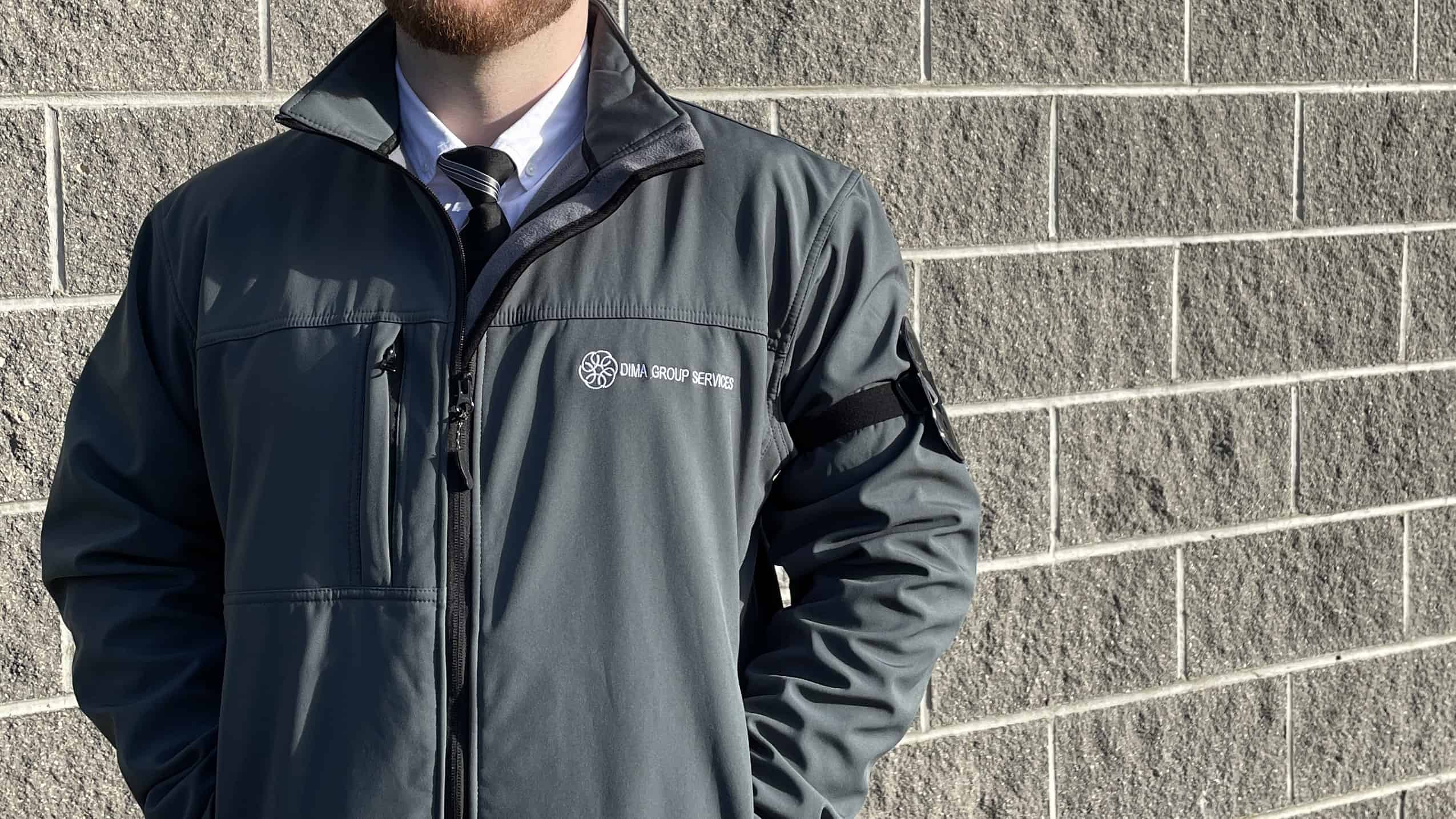 manned guarding_DIMA Security guard standing against a wall with the company uniform on